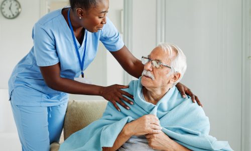Doctor or nurse caregiver with senior man, covering her with a blanket, helping and taking care of, at home or nursing home
