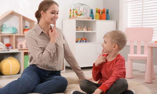 Speech therapist working with little boy in office